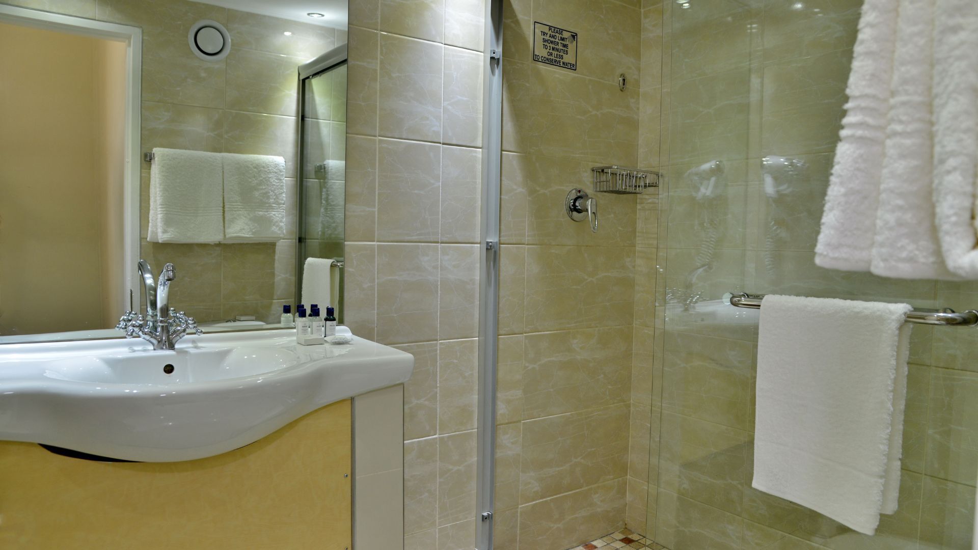 A bathroom with a sink, mirror, and shower.