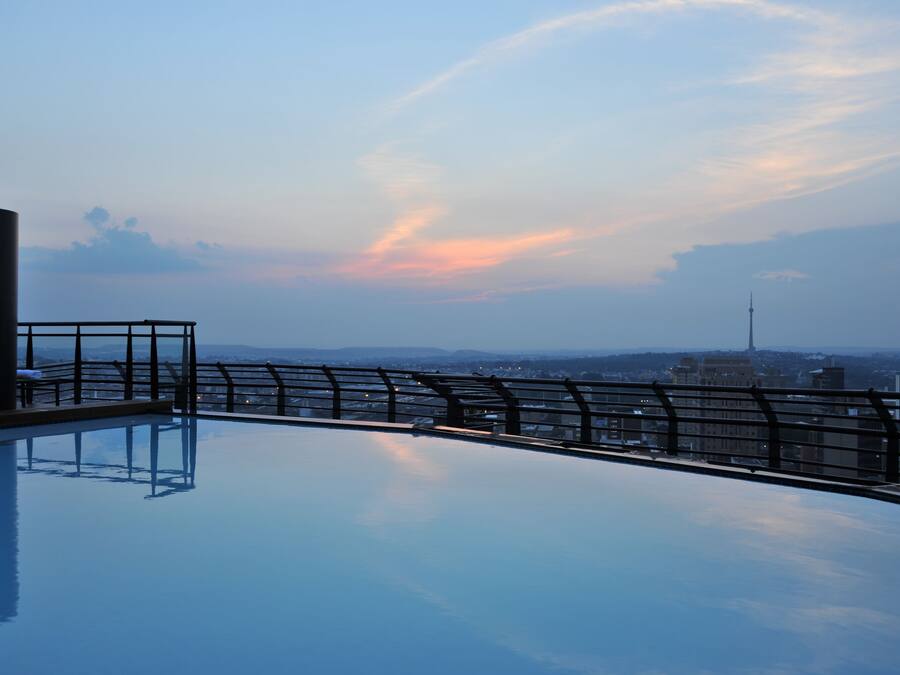 A rooftop pool with a metal railing and a cityscape view in the background.