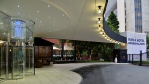 Exterior del Protea Hotel Parktonian All Suite, con entrada curva, ascensor de vidrio, asientos al aire libre y una fuente.