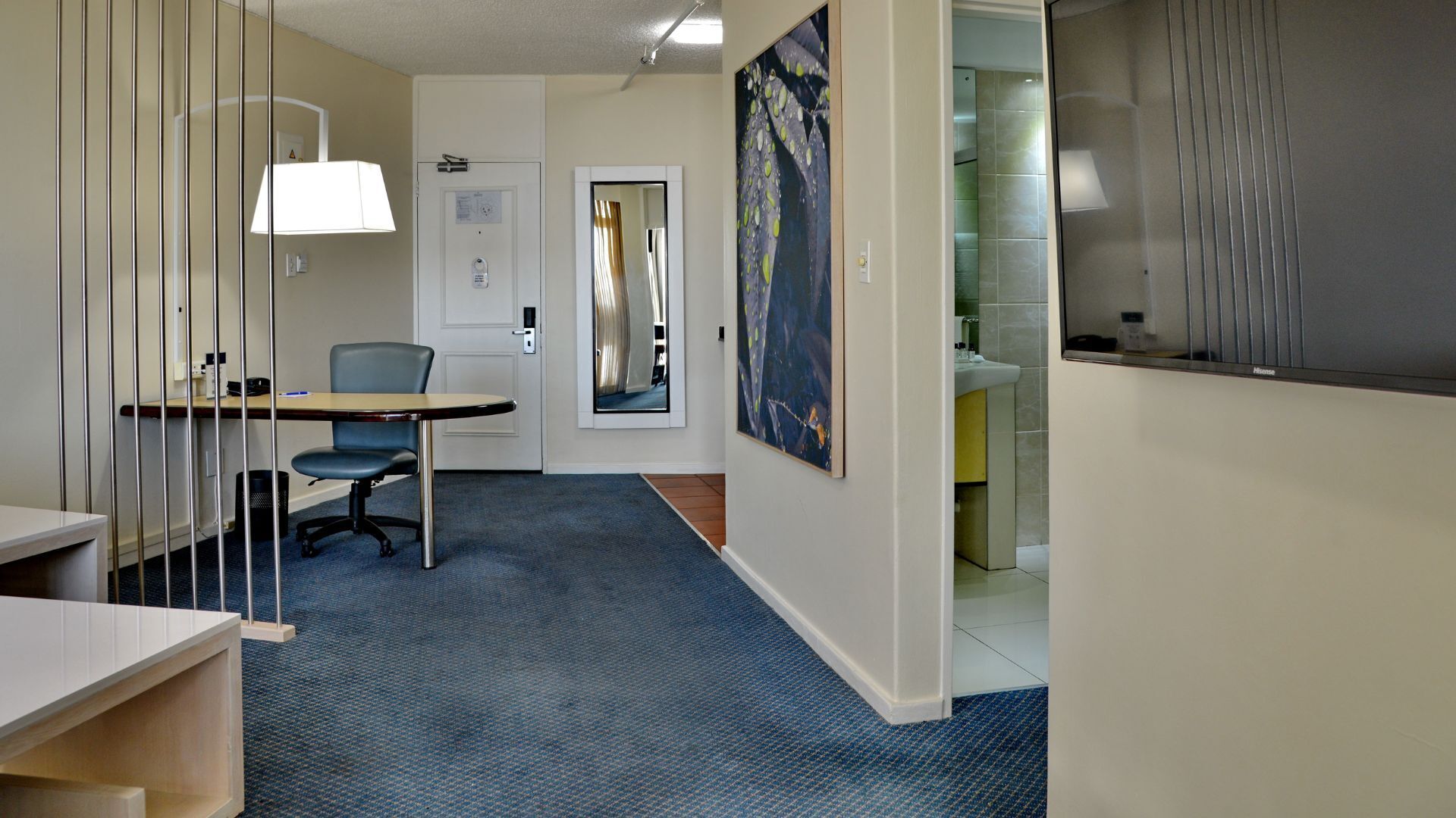 A modern office space with a desk, chair, and a large painting on the wall.
