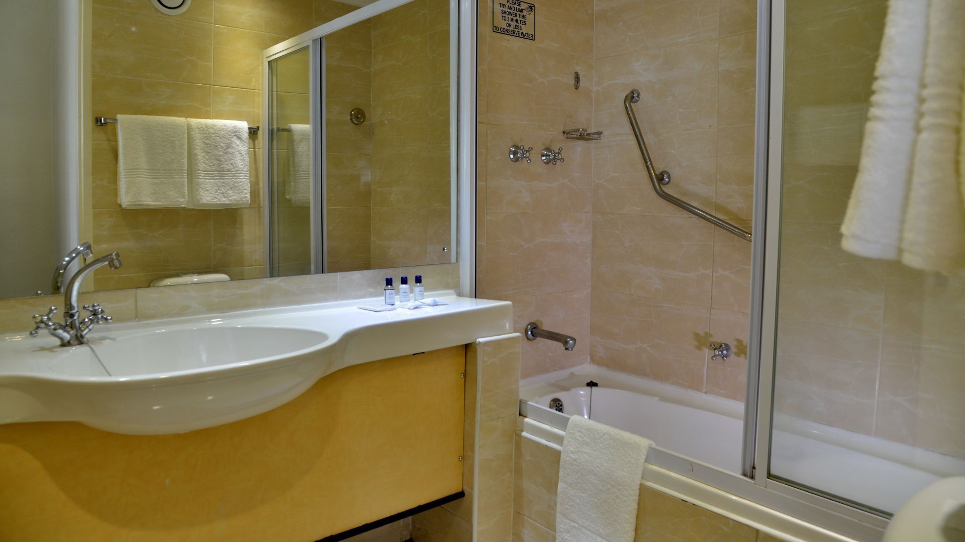 A bathroom with a sink, mirror, and shower.