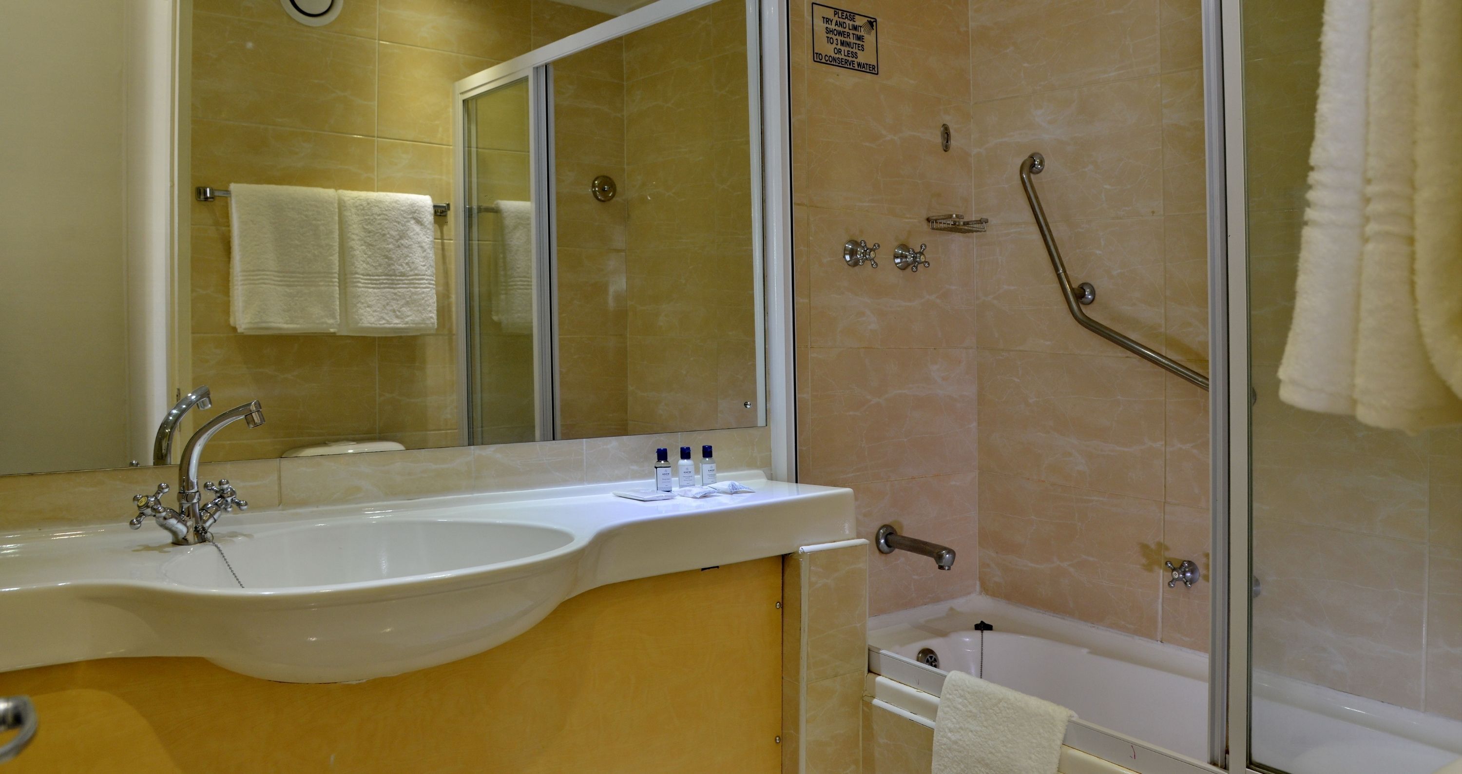 Un baño con lavamanos, espejo y zona de ducha.