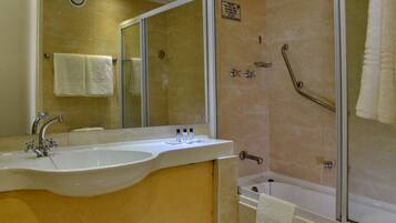 Un baño con lavamanos, espejo y zona de ducha.
