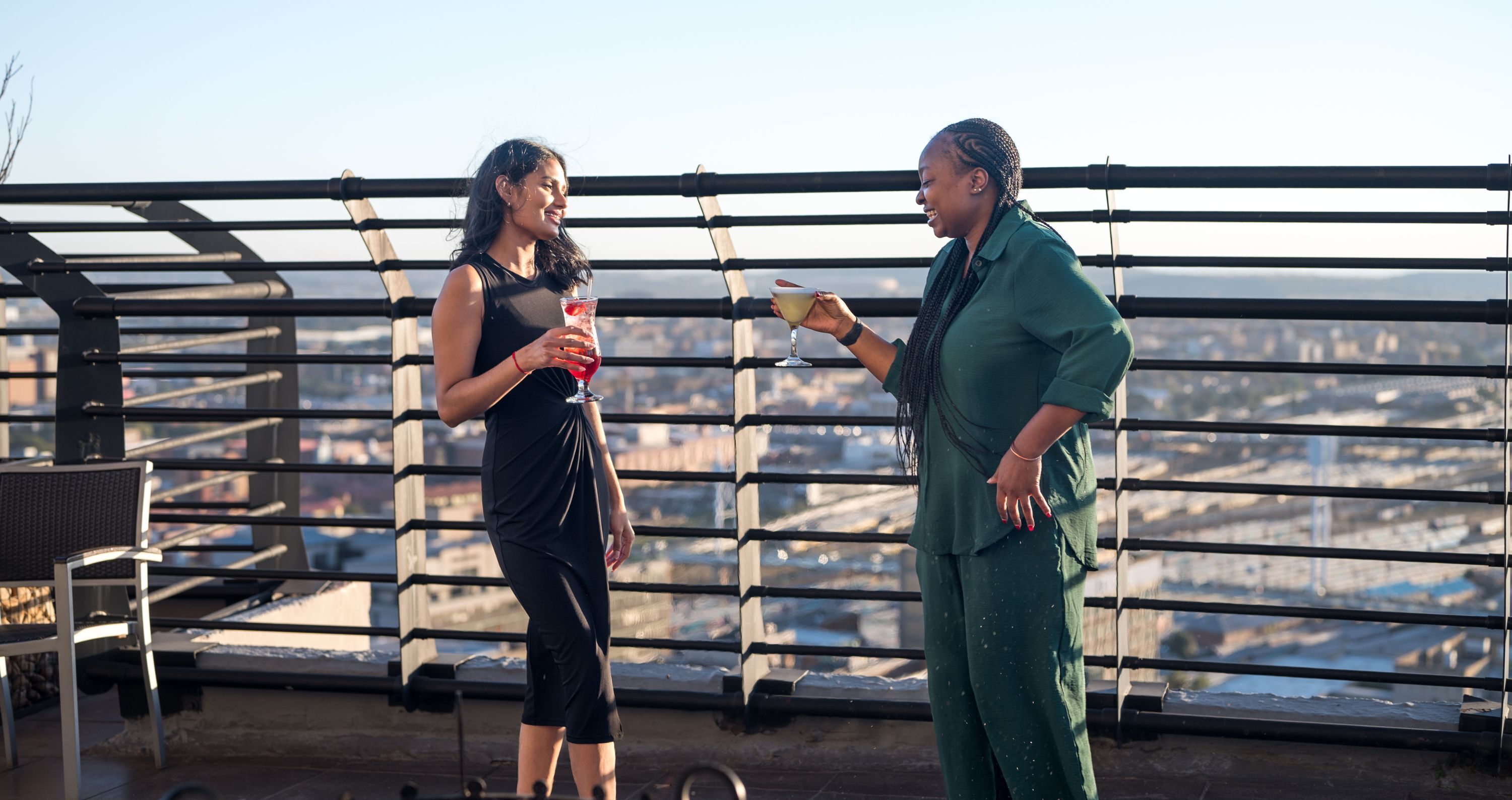 Zwei Personen stehen auf einer Dachterrasse mit Blick auf die Stadt.