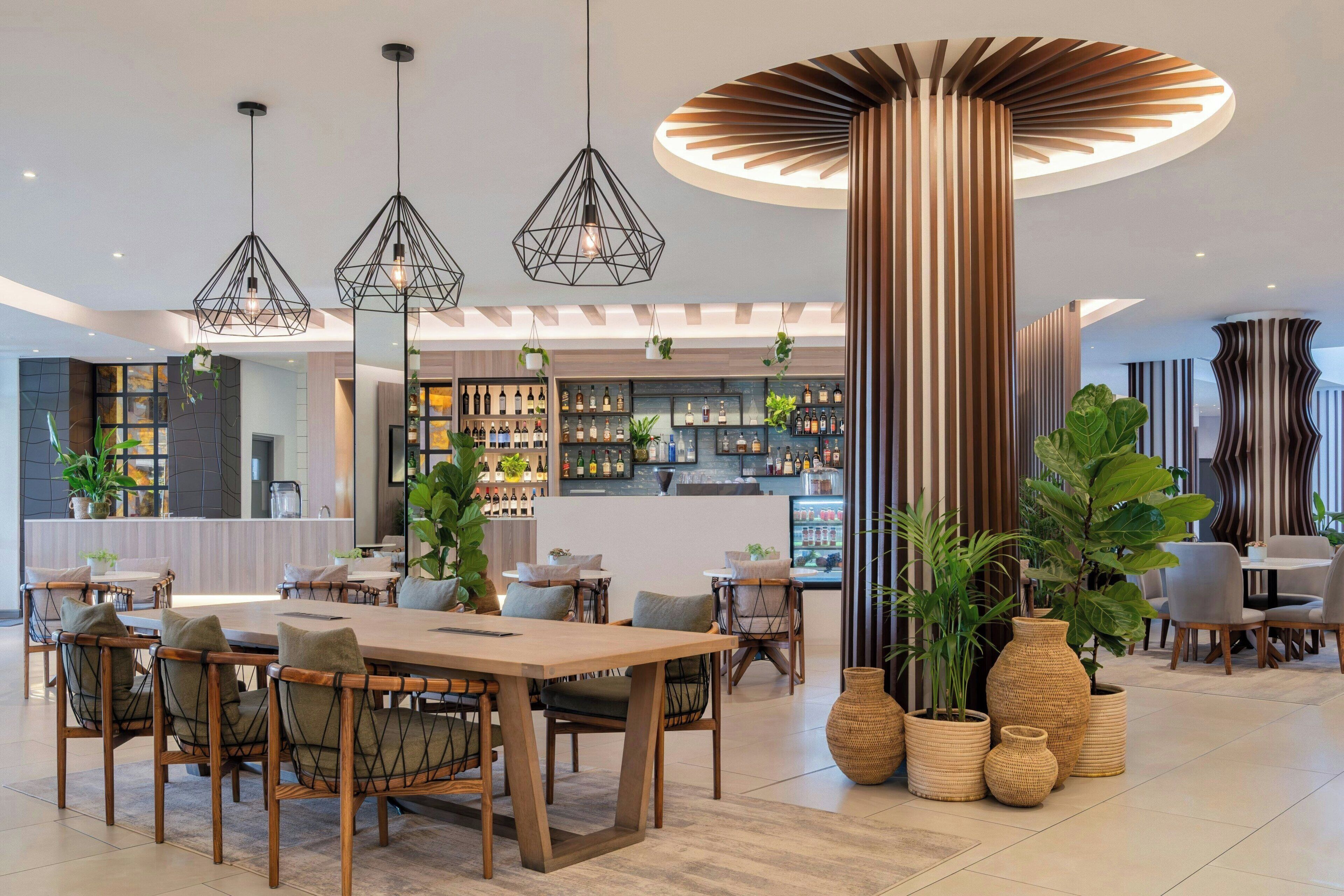 Un interior moderno con barra, asientos y plantas decorativas.
