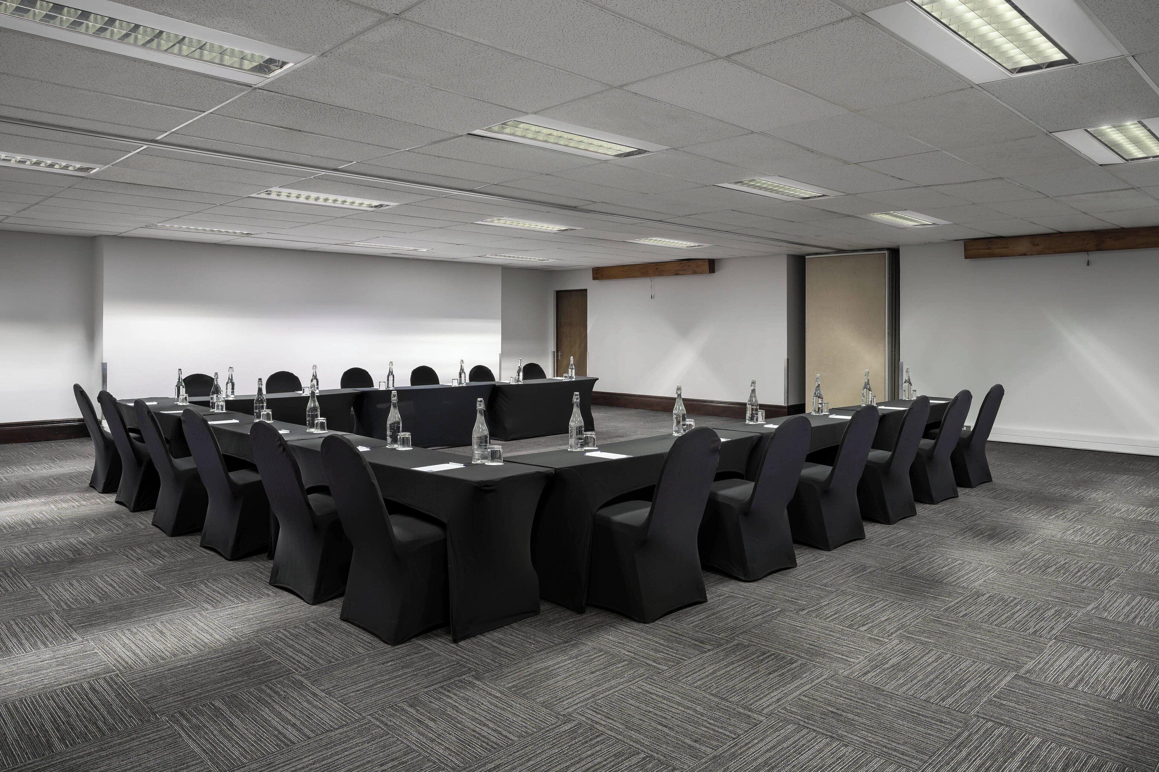 A conference room with a long table, multiple chairs, and water bottles.