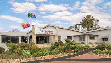 The Wanderers Golf Club with a stone facade, a flagpole with multiple flags, and a well-maintained landscaped area.
