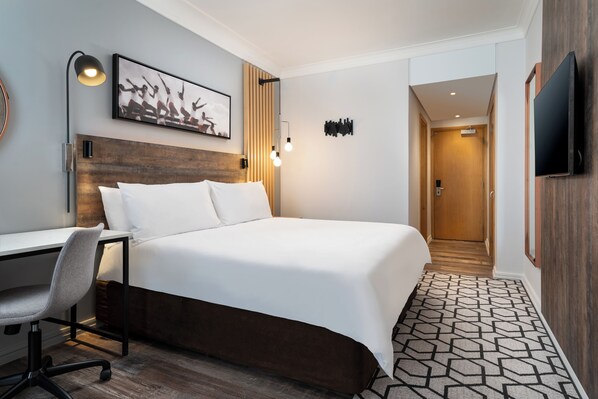 Una habitación de hotel con cama, escritorio, silla y televisión.