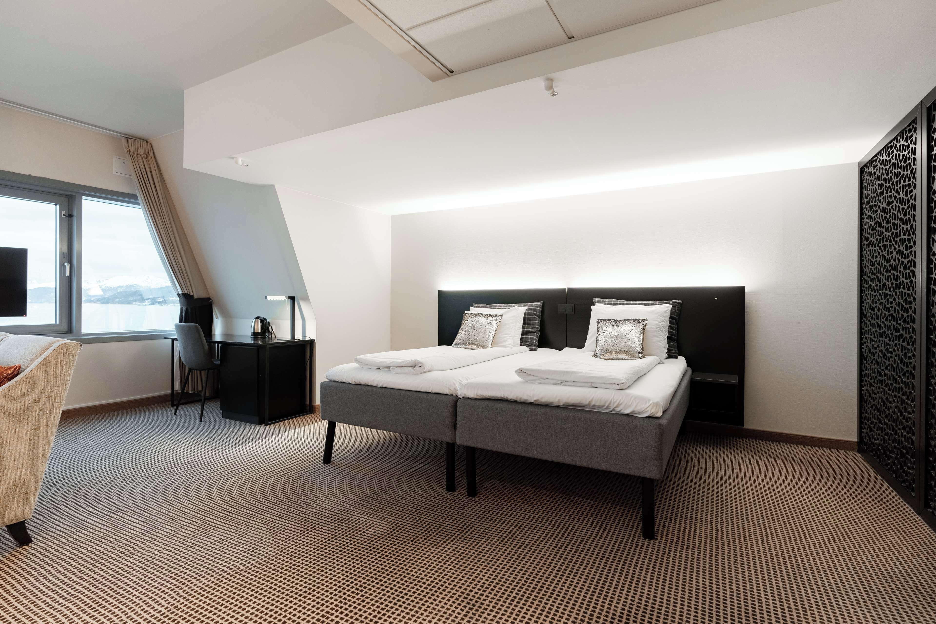 Una habitación de hotel moderna con una cama grande, un escritorio y vistas al exterior.