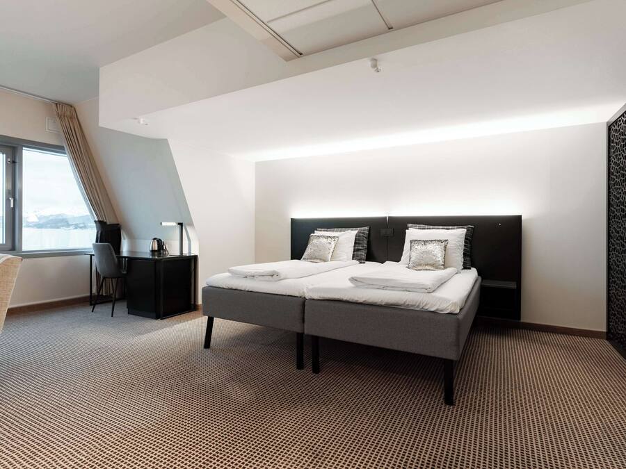 Una habitación de hotel moderna con una cama grande, un escritorio y vistas al exterior.