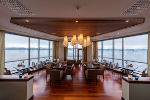 A spacious dining area with high ceilings, large windows, and a view of the sea. - Scandic Seilet (Molde)