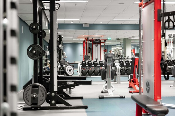 Un gimnasio con diversos equipos de ejercicio, incluyendo máquinas de pesas y mancuernas.