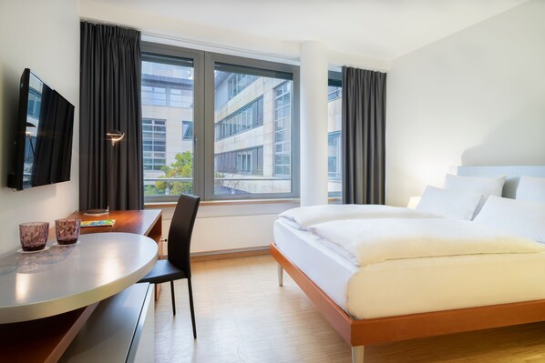 A modern hotel room with a large bed, a desk with two glasses, and a TV on the wall. - Four Points by Sheraton Munich Messe (Aschheim)