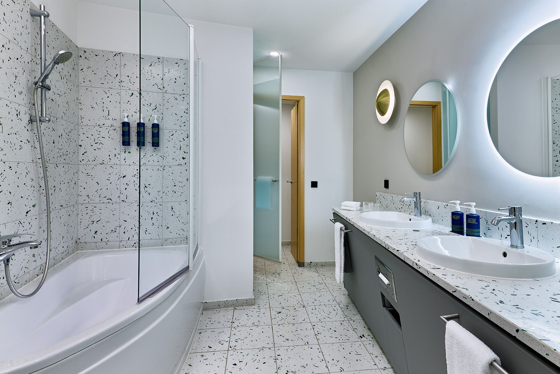 A modern bathroom with a glass-enclosed shower, two sinks, and a large mirror.