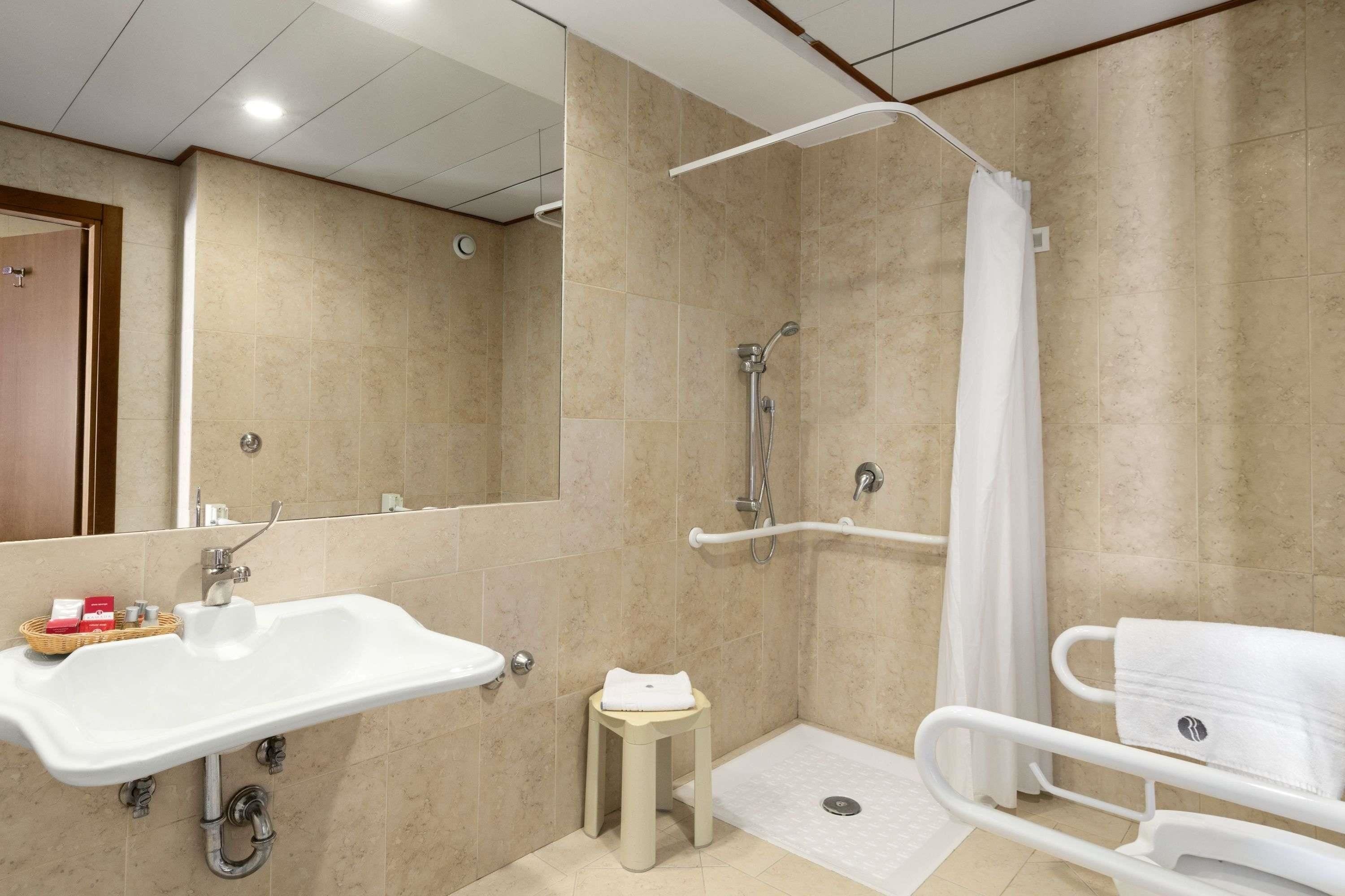 Une salle de bain équipée d’un lavabo, d’une douche et d’un banc accessible aux personnes en fauteuil roulant.