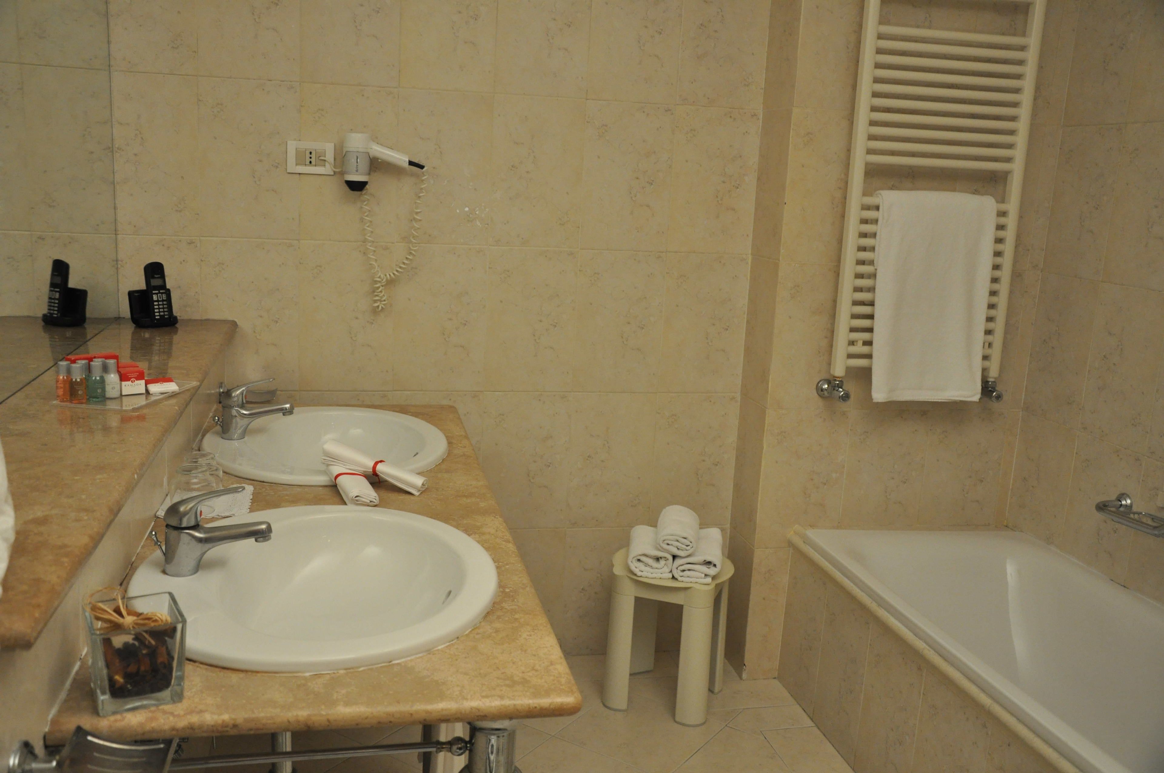 A bathroom with two sinks, a hairdryer, a towel rack, and a bathtub.