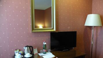 Una habitación de hotel con escritorio, televisor, lámpara y espejo.