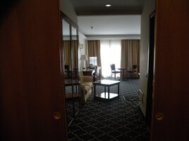 Una camera d'albergo con tappeto a motivi, una scrivania con sedia, un divano e un tavolo da pranzo con sedie.