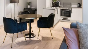 A modern kitchen with white cabinets, a built-in oven, and a coffee maker. There is a round table with two chairs in the dining area. - Frogner House - Bygdøy Allé (Oslo)