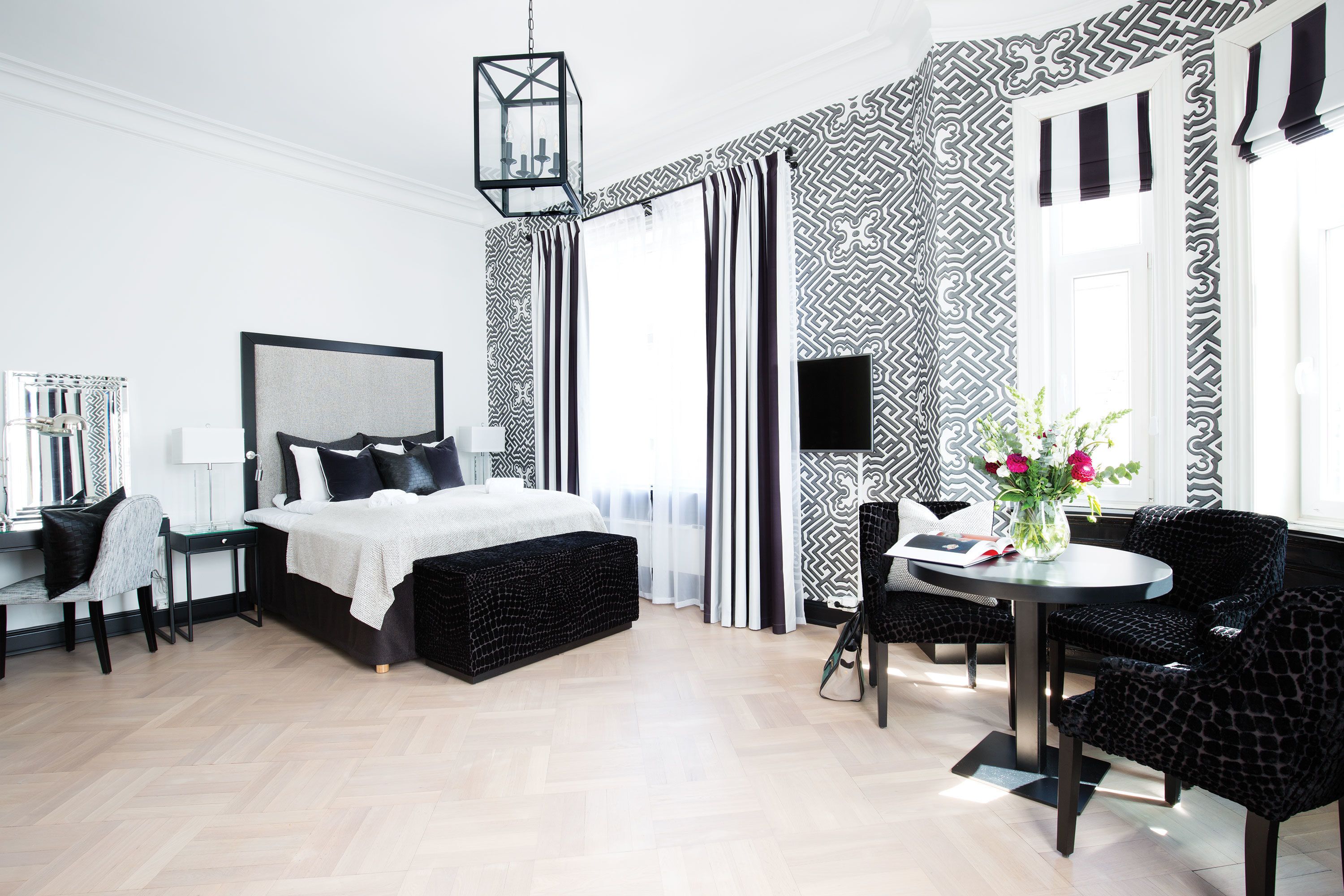 A modern bedroom with a bed, bedside tables, a desk, and a chair.