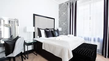A modern hotel room with a large bed, a bedside table, a chair, and a large window with curtains.