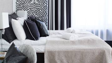 Una cama bien hecha con sábanas blancas y un cabecero estampado.