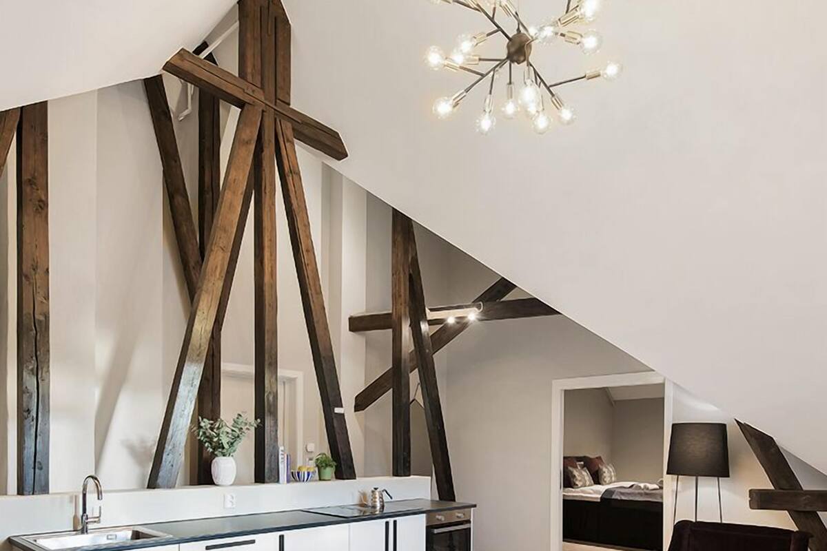 A modern kitchen with a central island, exposed wooden beams, and a contemporary chandelier.