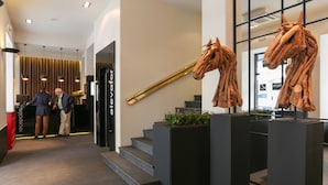 Ein moderner Empfangsbereich mit einer Treppe, Holzpferd-Skulpturen und einem Empfängeschalter.