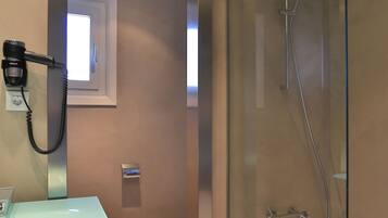 A modern bathroom with a glass-enclosed shower, a standalone sink, and a toilet.