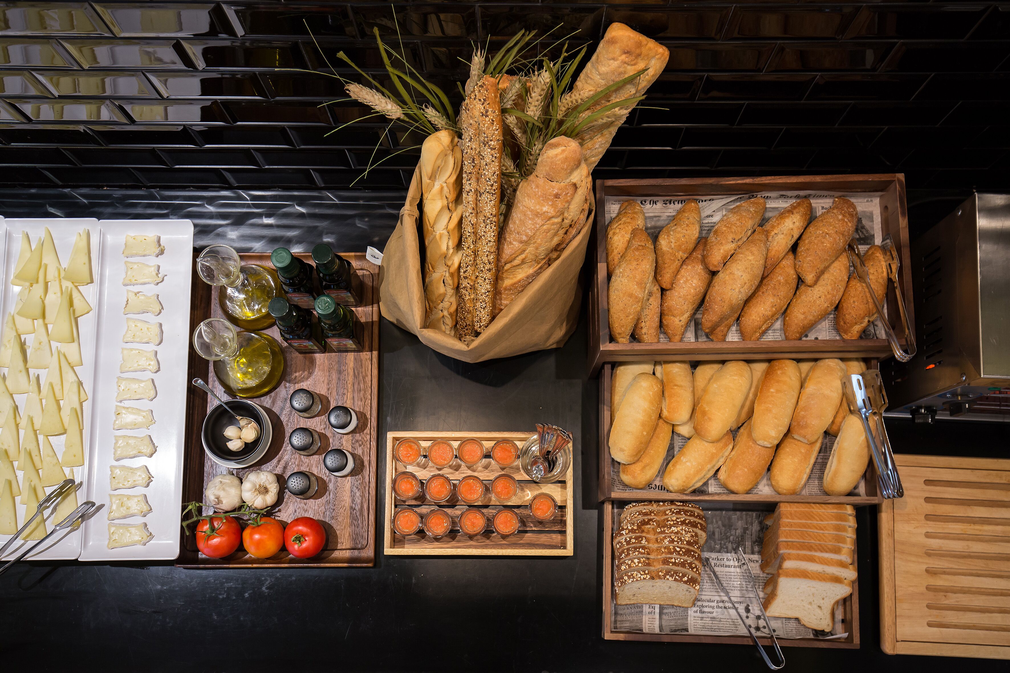 Diverse etenswaren, zoals brood, kaas, tomaten en olijven, gerangschikt op een tafel.