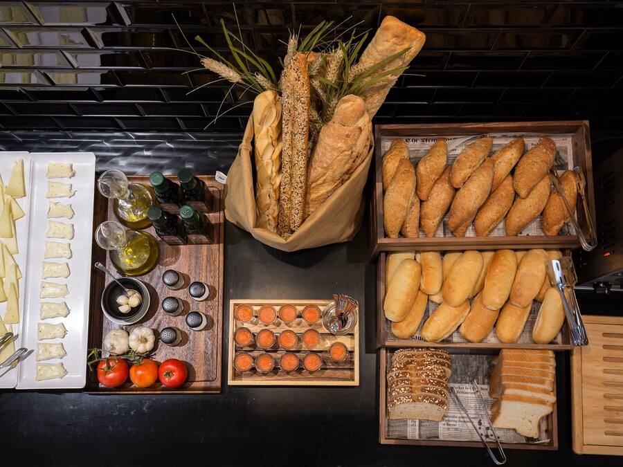 Diverse etenswaren, zoals brood, kaas, tomaten en olijven, gerangschikt op een tafel.