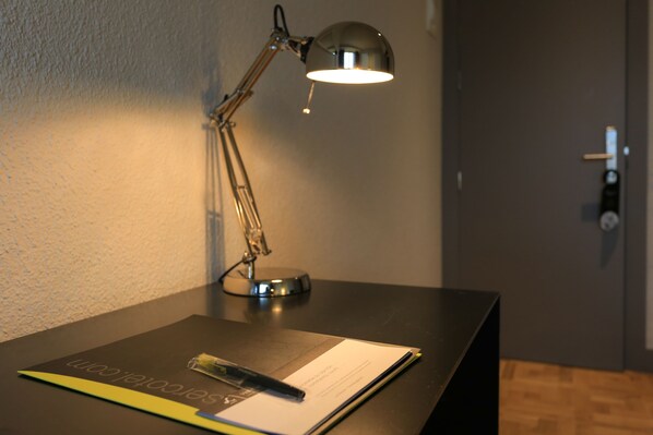 A desk with a desk lamp, a notepad, and a pen. - Hotel Leyre (Pamplona)