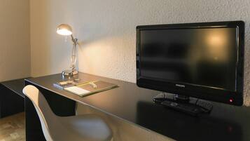 Un escritorio moderno con un monitor Philips, una lámpara y una silla.