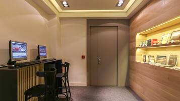 Un mostrador de recepción con dos monitores de computadora, un panel de pared de madera y una puerta.