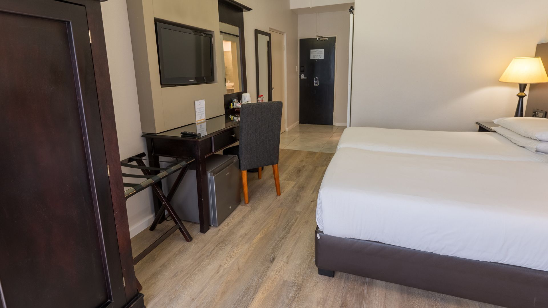 A hotel room with a bed, desk, chair, and a TV.