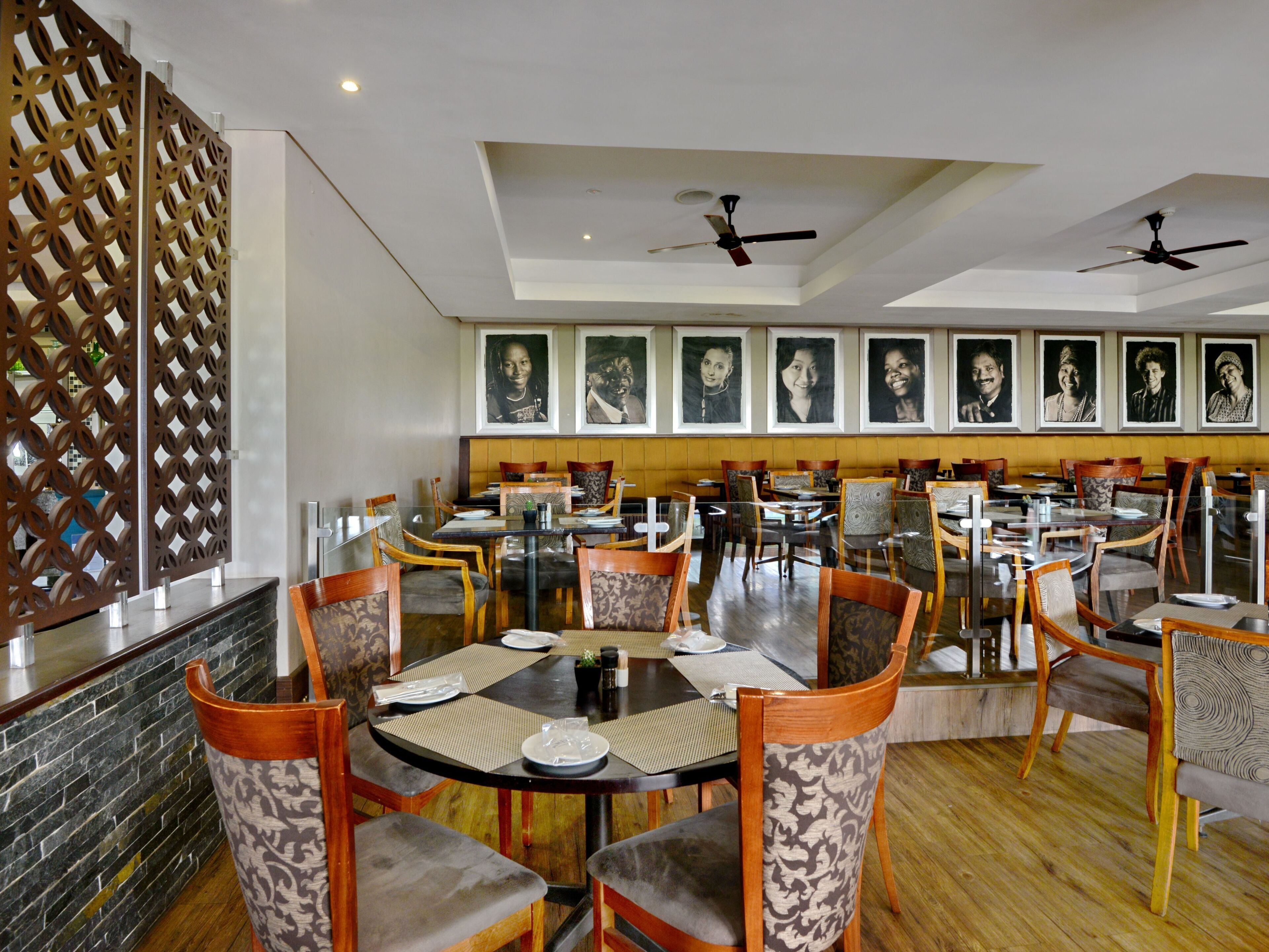 A restaurant with round tables, chairs, and ceiling fans.