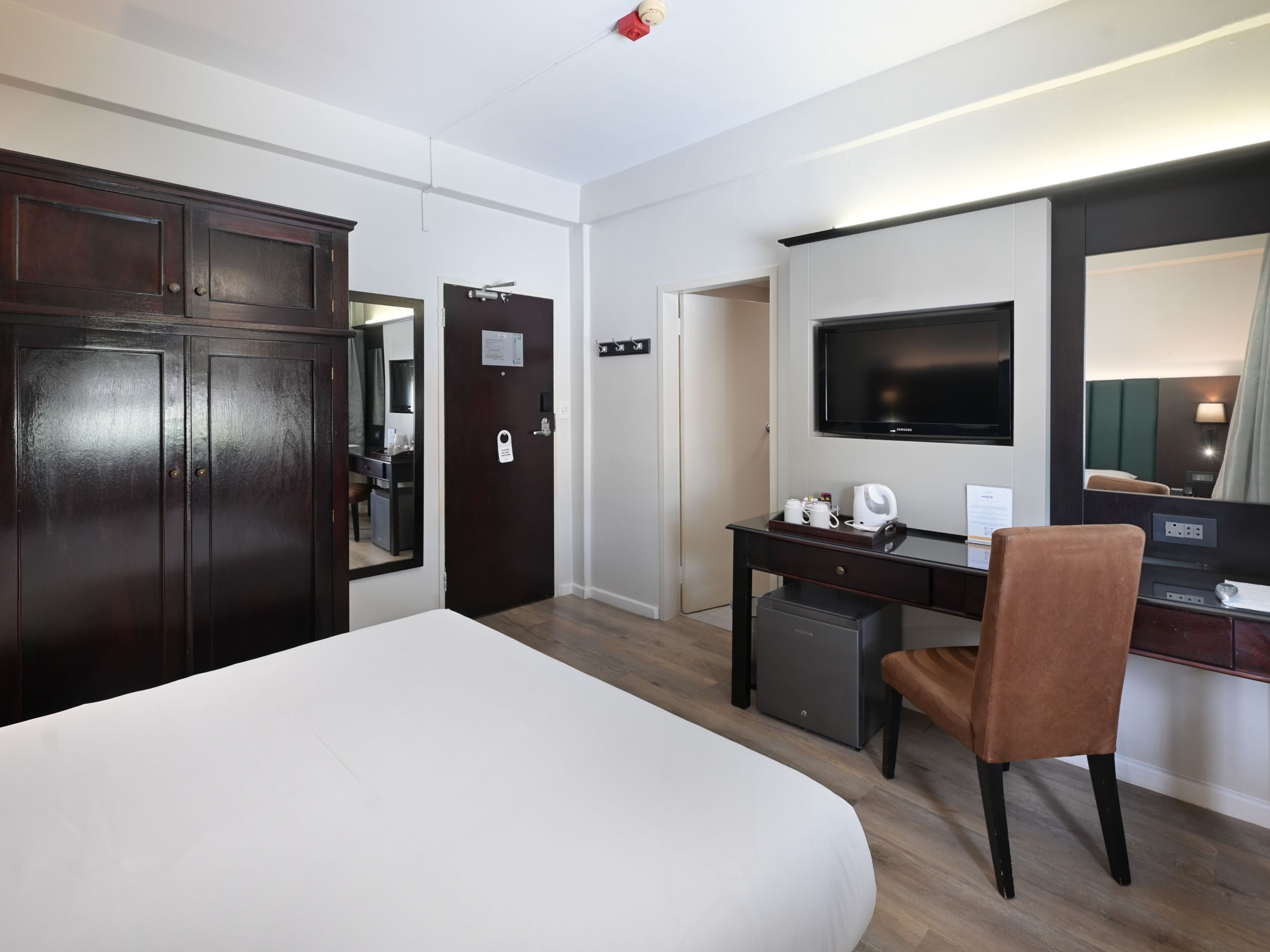 Una habitación de hotel con una cama grande, un escritorio con silla, un televisor y un armario.
