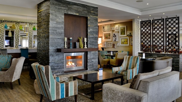 Un espacio lounge moderno con chimenea de piedra, asientos cómodos y una zona de bar con detalles decorativos.