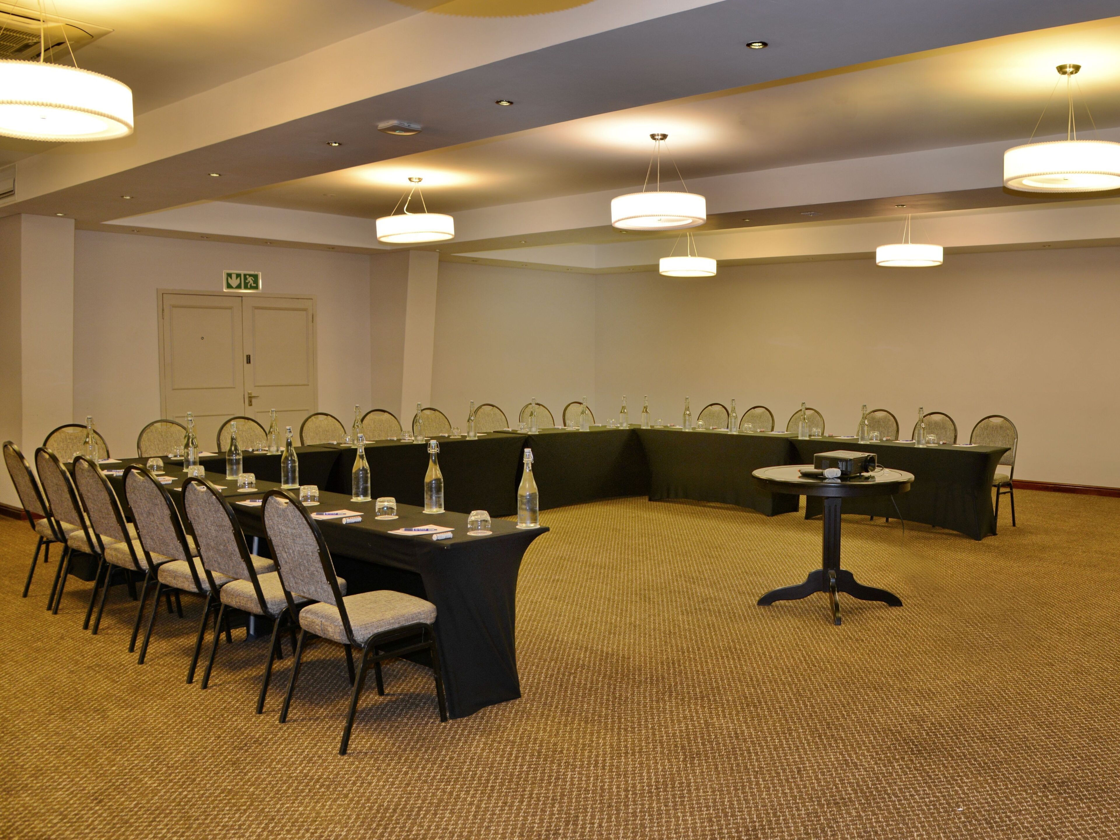 Un salón de conferencias con una mesa grande, sillas y una mesa más pequeña con un reloj.