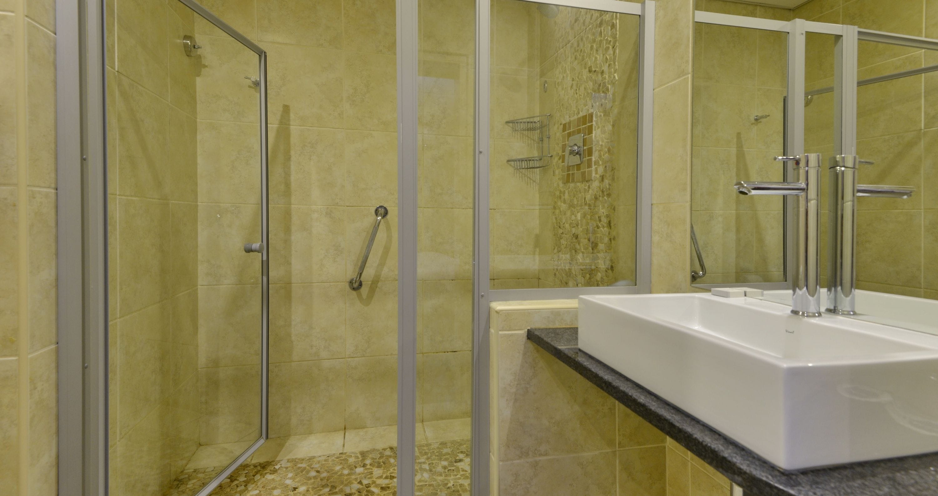 A bathroom with a glass-enclosed shower, a white sink, and a tiled floor.