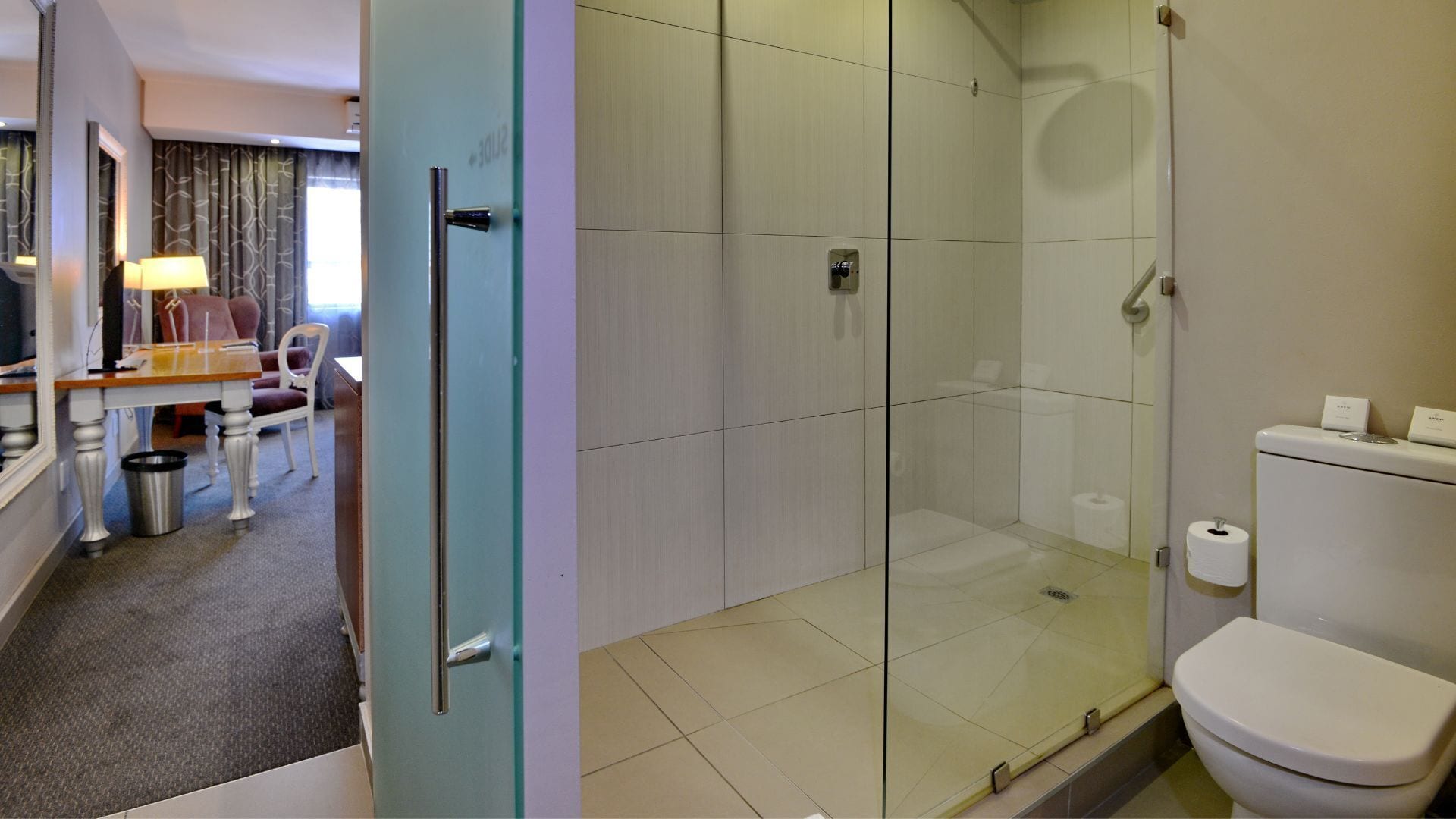 A hotel bathroom with a glass-enclosed shower, a toilet, and a sink.