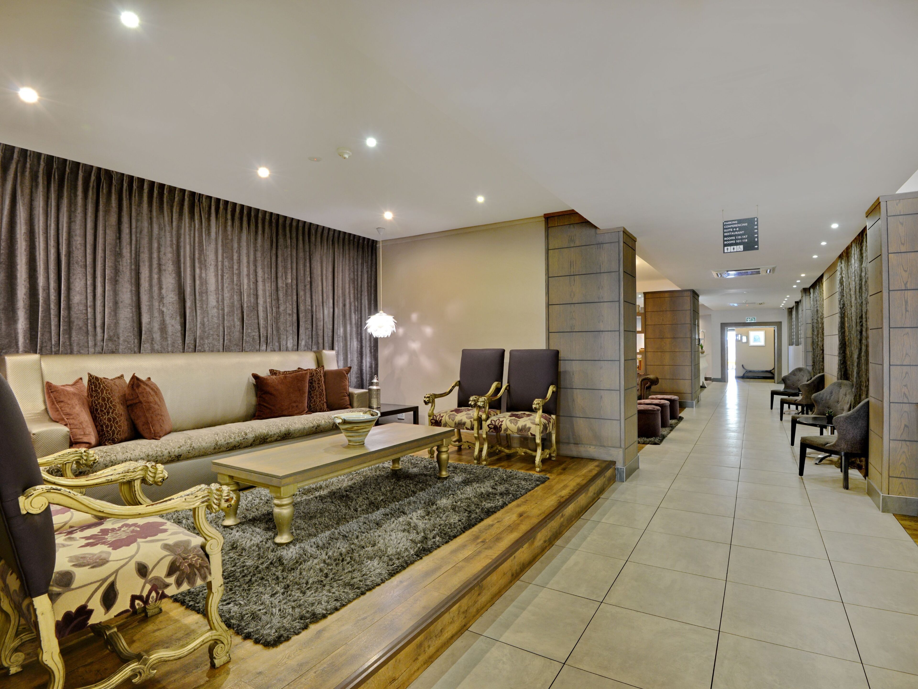 En moderne hotellobby med sofa, stole, sofabord og reception.