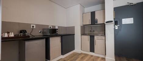 A compact kitchen with a microwave, coffee machine, and a small refrigerator.