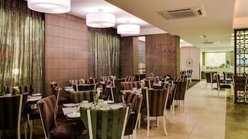 Un restaurant doté de nombreuses tables et chaises, d’un mur décoratif et de luminaires suspendus.