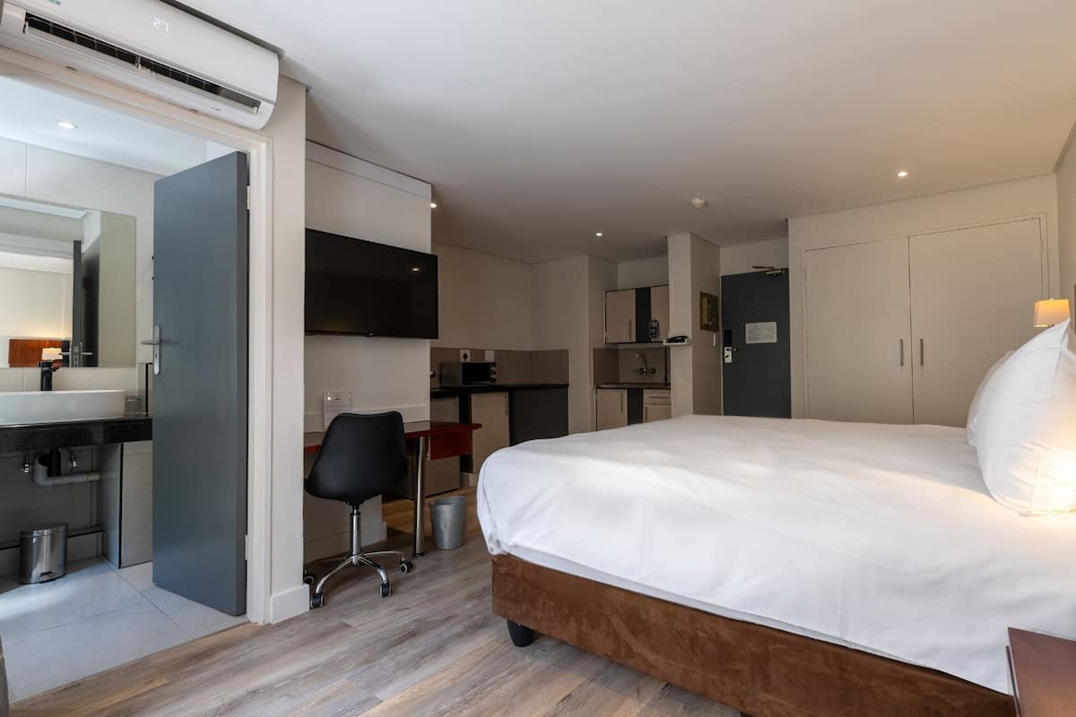 Une chambre d’hôtel moderne dotée d’un grand lit, d’un bureau et d’une kitchenette.