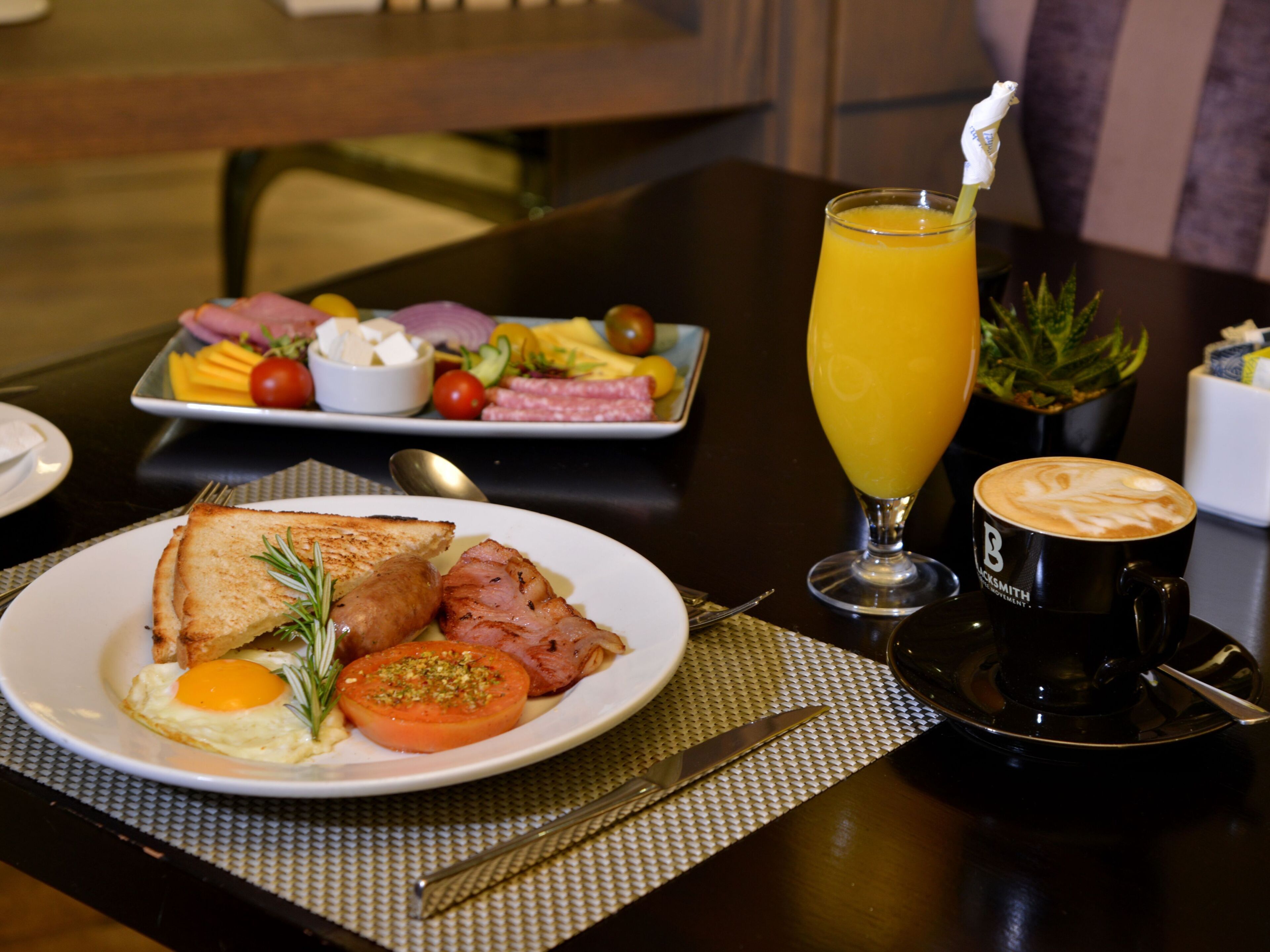A breakfast setting with toast, eggs, bacon, and a fruit plate.