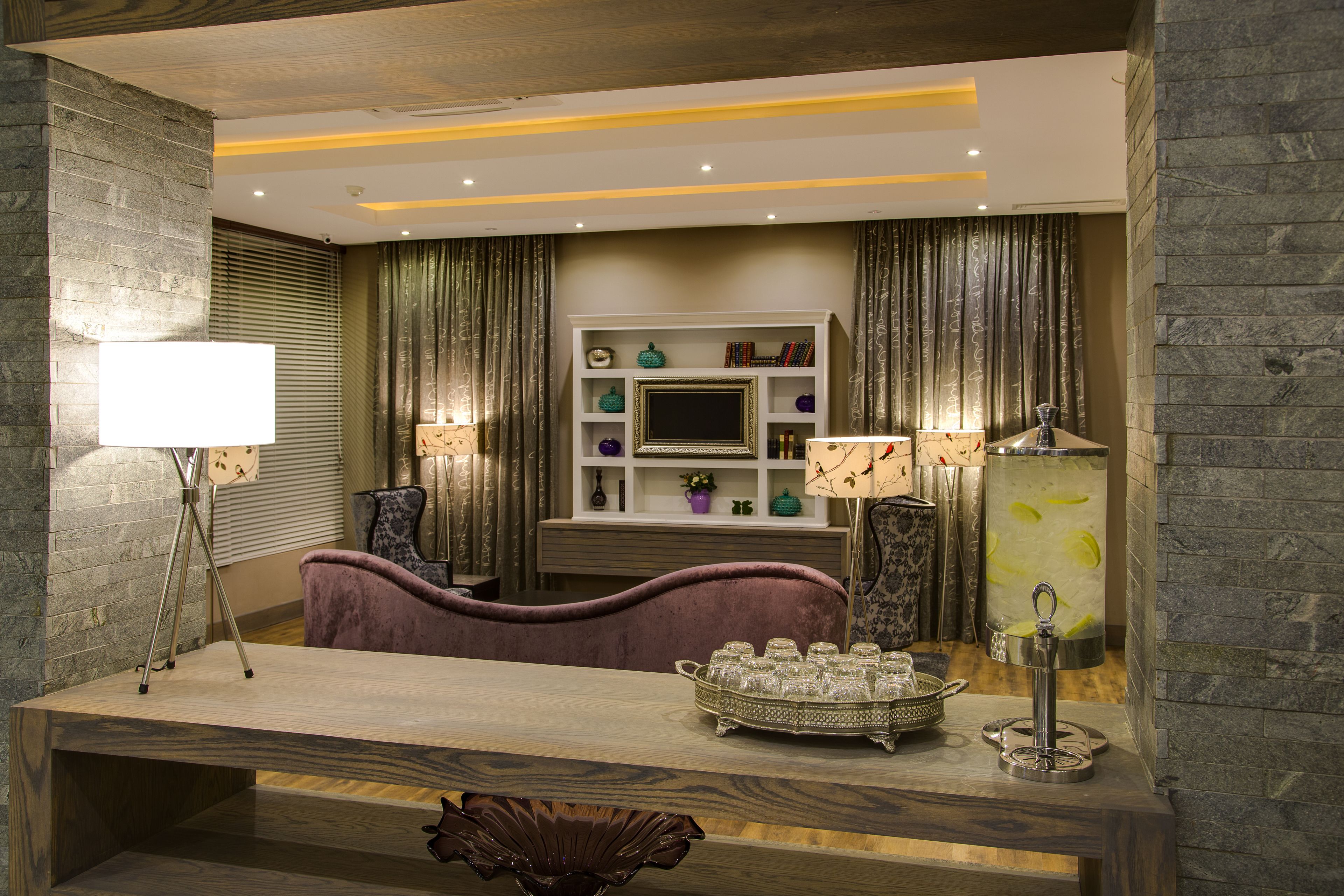 A modern living room with a wooden coffee table, a purple sofa, and a TV stand with decorative items.