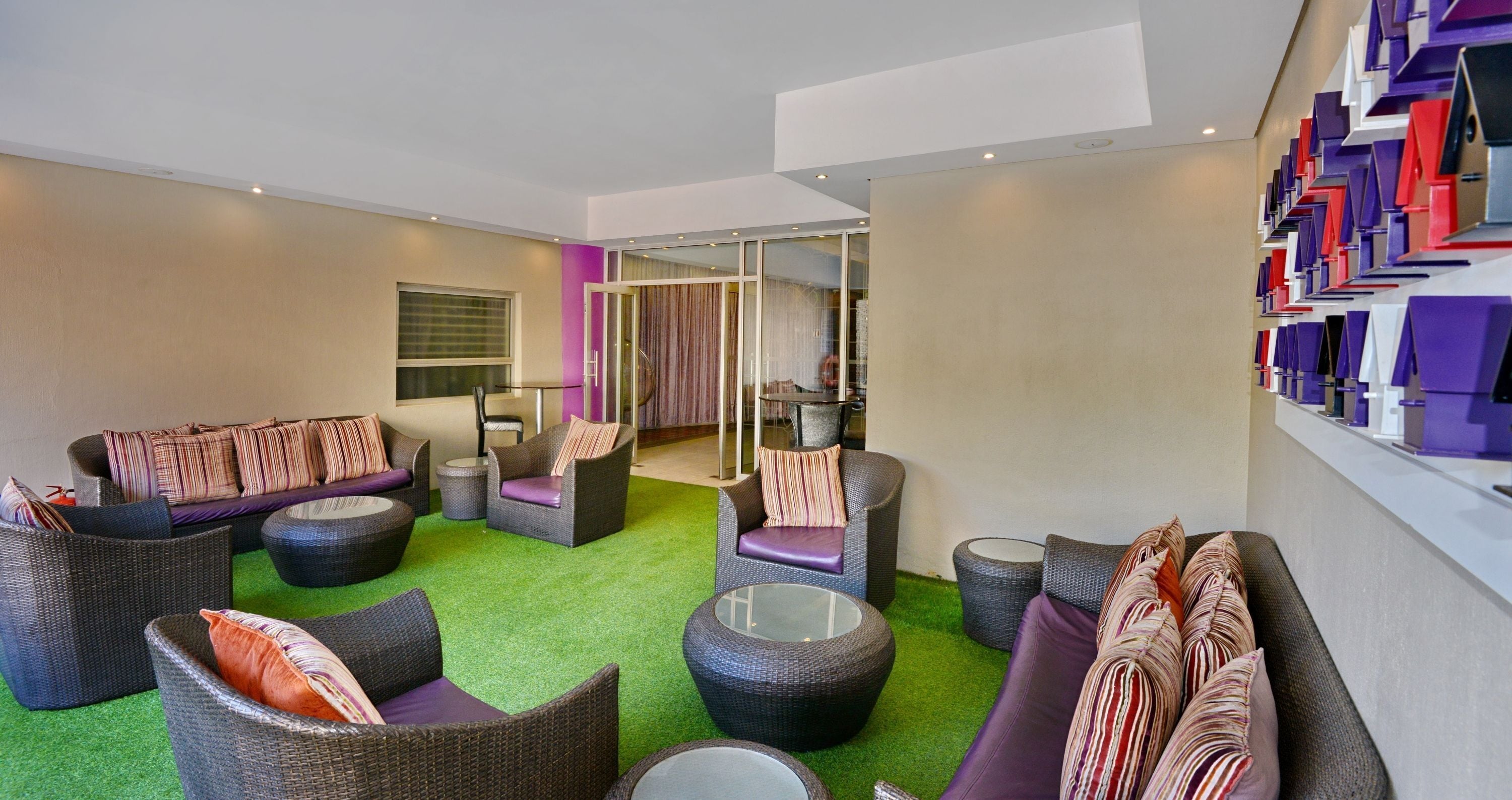 Un'area lounge moderna con mobili in vimini, un tavolino in vetro e un tappeto verde.