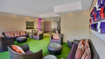 Un'area lounge moderna con mobili in vimini, un tavolino in vetro e un tappeto verde.
