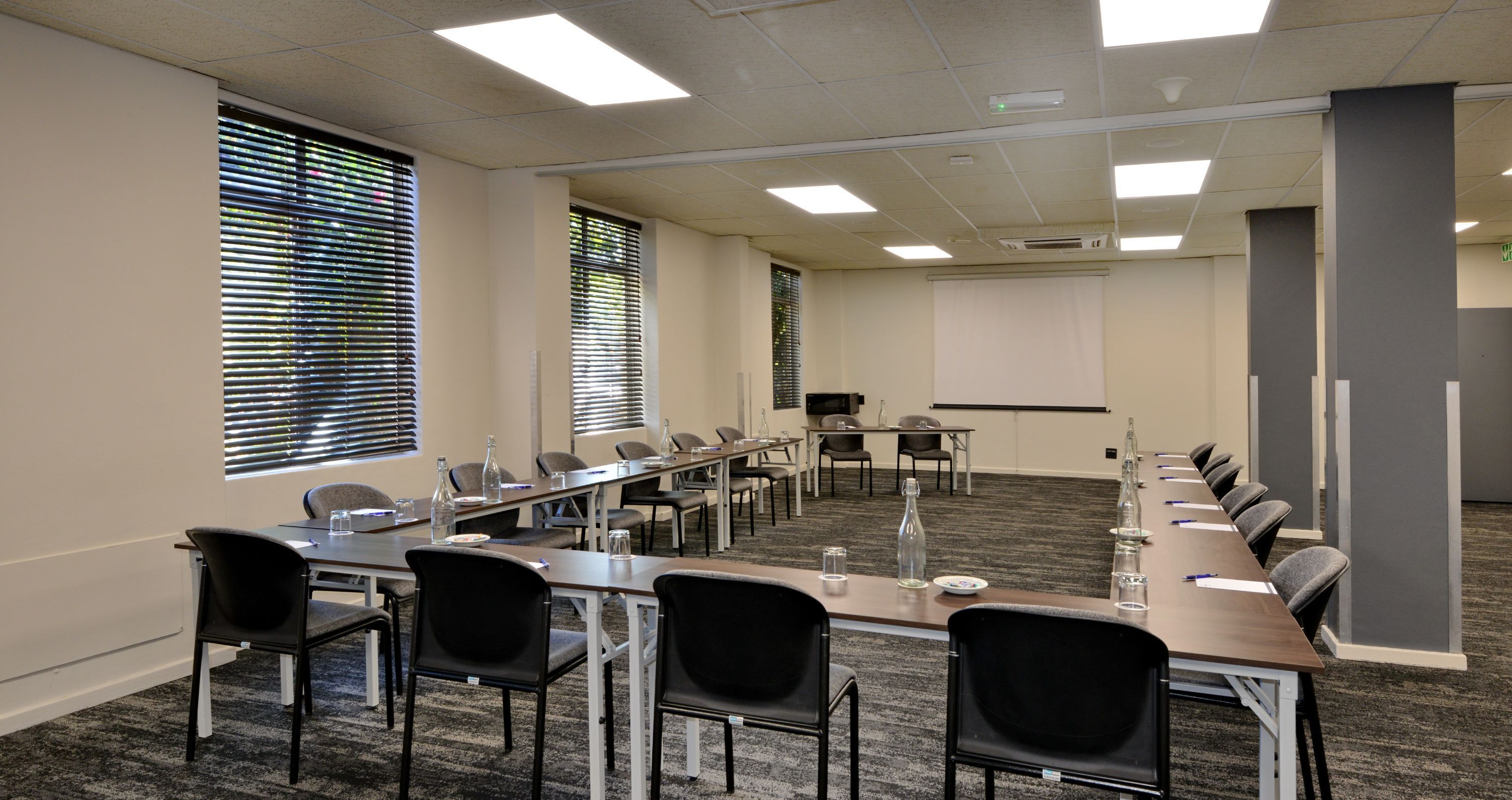 Une salle de conférence équipée d’une longue table, de chaises et d’un écran de projection.